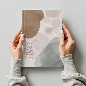 May include: A notebook with an abstract design featuring brown, gray, and pink watercolor shapes. The notebook has a textured paper cover.