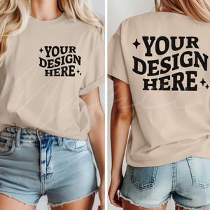 以下が含まれることがあります： ベージュのTシャツ、袖はロールアップされ、黒で「YOUR DESIGN HERE」の文字と星のアクセント。デザインは前面と背面にあります。モデルは青いジーンズのショートパンツを着用しています。