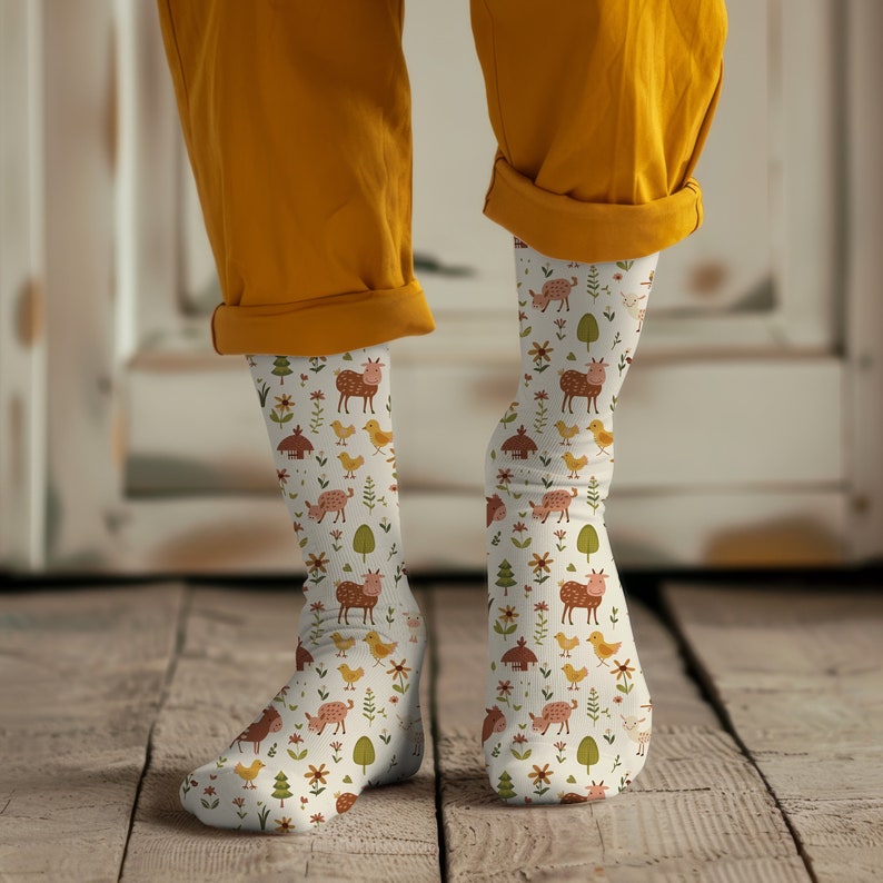 May include: A pair of white socks with a colorful pattern of farm animals, flowers, and houses. The socks are worn on a person's legs, with the tops of the socks folded down.