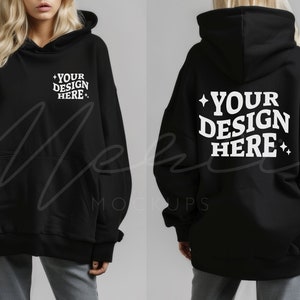 Puede incluir: Sudadera con capucha negra con bolsillo delantero y capucha. La parte delantera de la sudadera tiene el texto "YOUR DESIGN HERE" en blanco. La parte trasera de la sudadera también tiene el texto "YOUR DESIGN HERE" en blanco.