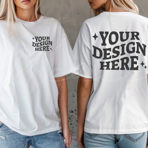 以下が含まれることがあります： 「YOUR DESIGN HERE」という文字が印刷された白いTシャツが2枚。1枚は前面に、もう1枚は背面に文字が印刷されています。