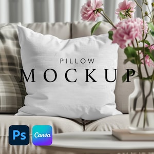 May include: White pillow mockup on a beige couch with a vase of pink flowers. The pillow has the text "PILLOW MOCKUP" printed on it.
