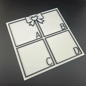 May include: A white square divided into four sections with black borders. A black bow with a heart in the center is at the top. The letters A, B, C, and D are in each section.