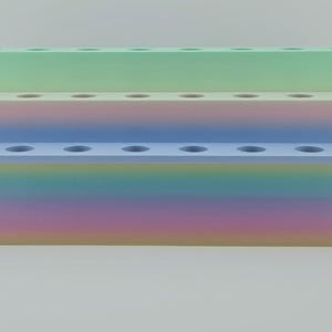 May include: A three-tiered rectangular display stand featuring a gradient color scheme. The top tier is light green, the middle tier transitions from pink to blue, and the bottom tier displays a multi-colored rainbow gradient with circular holes.