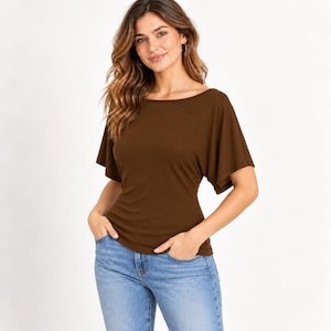 May include: A dark brown short-sleeved top featuring a wide boat neckline and loose, flowing flutter sleeves. The garment has a fitted bodice that tapers at the waist, paired with light blue denim jeans that have a classic five-pocket design.