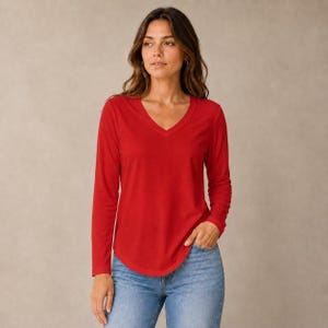 May include: A long-sleeve shirt in a solid red color featuring a V-neckline and a curved hemline. The shirt is paired with light blue denim jeans that have a classic five-pocket design and a medium wash finish with subtle fading on the thighs.