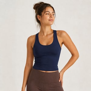 May include: A solid navy blue racerback tank top with a scoop neckline and a fitted silhouette. The garment features a simple, sleeveless design with wide shoulder straps, providing a clean and streamlined look for athletic or casual wear.