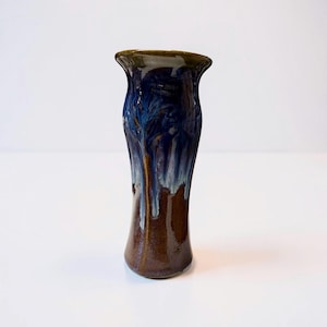 May include: A tall, handcrafted ceramic vase with a flared rim. The vase features a rich color palette, with a dark brown base that transitions to a deep blue and white glaze, creating a dripped effect. The vase is a decorative item.
