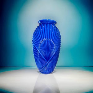 May include: A cobalt blue glass vase with a unique fan-shaped design. The vase is tall and slender, with a rounded base and a narrow opening.