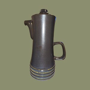 May include: A dark brown ceramic coffee pot with a wide base and a narrow spout. The pot has a green and blue glaze with a textured finish.