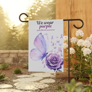 Puede incluir: Una bandera de jardín blanca con una mariposa y una rosa moradas. La bandera dice "We wear purple cystic fibrosis awareness".