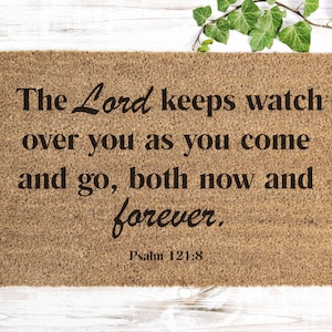 Peut inclure: Un paillasson brun avec le texte "The Lord keeps watch over you as you come and go, both now and forever. Psalm 121:8" imprimé en noir.