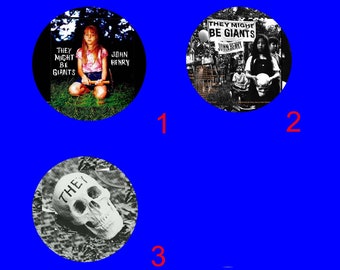 May include: Three black and white vinyl records with album covers featuring the band They Might Be Giants. The first album cover features a young girl holding a baseball bat. The second album cover features a group of people standing in front of a sign that says "They Might Be Giants". The third album cover features a skull with the word "They" written on it.