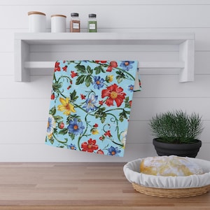 Könnte beinhalten: Ein blaues Küchentuch mit einem Blumenmuster mit roten, gelben und blauen Blumen auf hellblauem Hintergrund.
