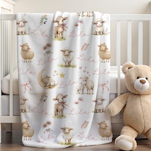 A personalized custom name white velveteen blanket with whimsical lambs, pink bows, stars, flowers, hearts and butterflies draped over a crib.