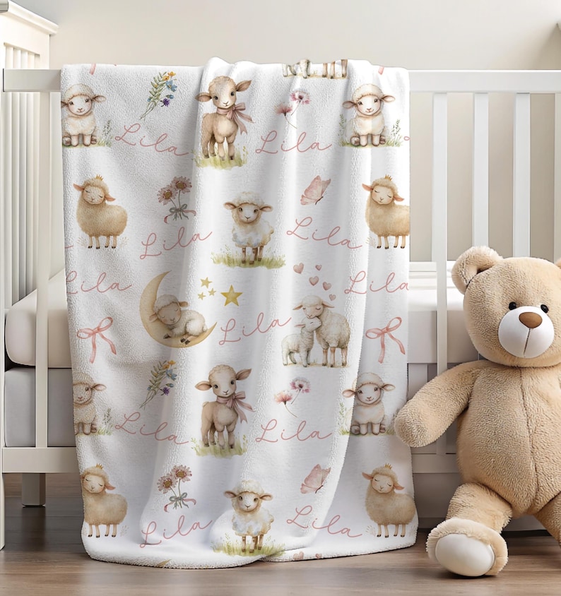 A personalized custom name white velveteen blanket with whimsical lambs, pink bows, stars, flowers, hearts and butterflies draped over a crib.