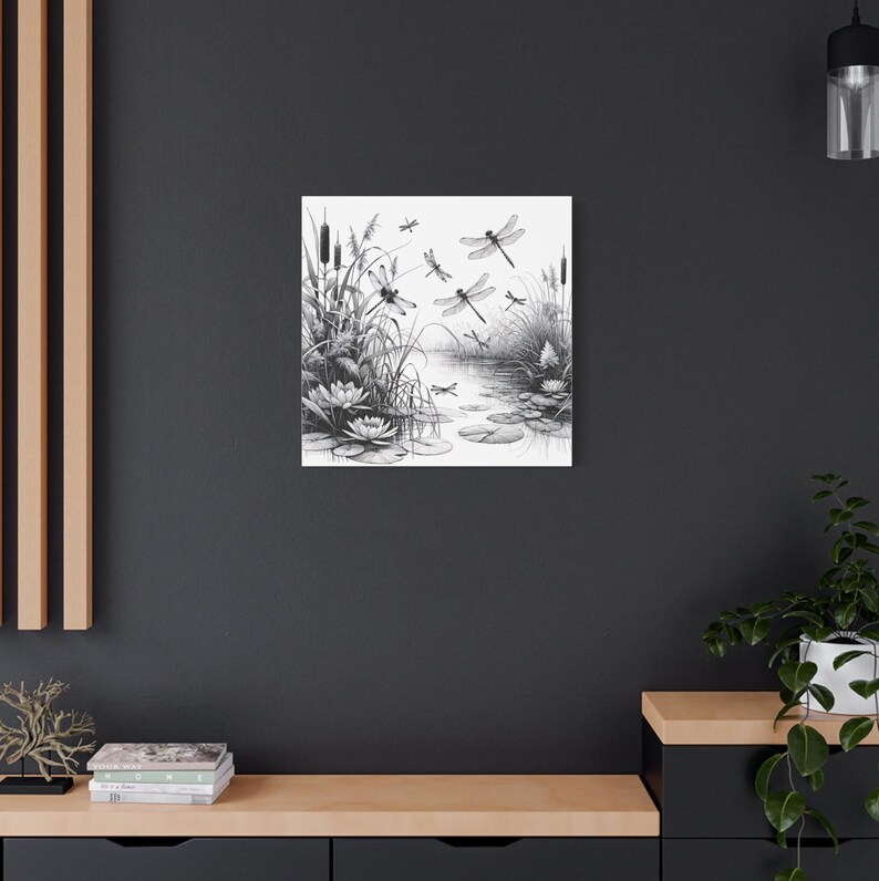 May include: Black and white canvas art print featuring a serene pond scene with dragonflies, lily pads, and reeds. The artwork is a detailed illustration, perfect for nature lovers and those seeking a calming aesthetic for their home decor.