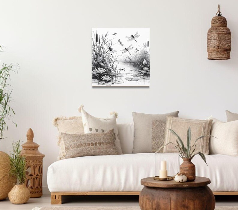 Canvas wall art above a couch. The canvas wall art features an elegant black and white line art scene of dragonflies gracefully hovering over a tranquil pond.