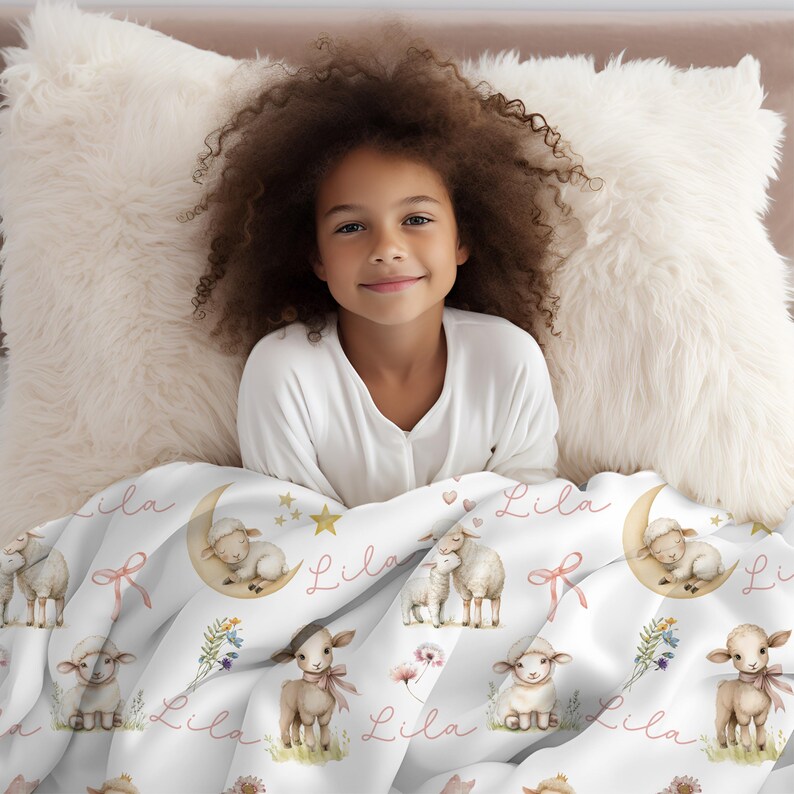 A little girl cuddled up with a personalized custom name white velveteen blanket with whimsical lambs, pink bows, stars, flowers, hearts and butterflies laying on the floor surrounded by toys.