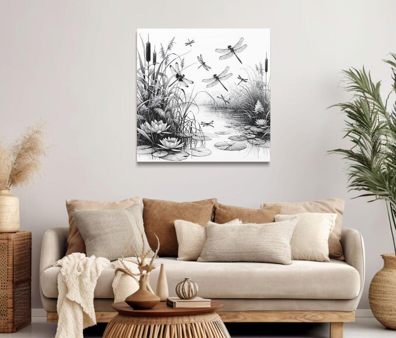 Canvas wall art above a couch. The canvas wall art features an elegant black and white line art scene of dragonflies gracefully hovering over a tranquil pond.