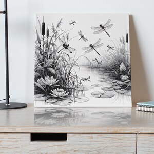 Canvas wall art on a dressser. Canvas wall art features an elegant black and white line art scene of dragonflies gracefully hovering over a tranquil pond.