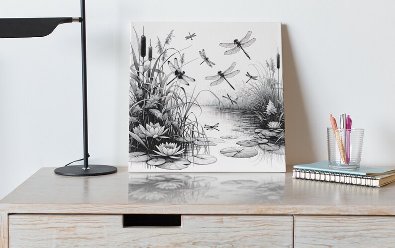 Canvas wall art on a dressser. Canvas wall art features an elegant black and white line art scene of dragonflies gracefully hovering over a tranquil pond.