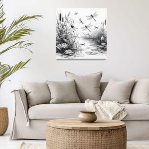 Canvas wall art above a couch. The canvas wall art features an elegant black and white line art scene of dragonflies gracefully hovering over a tranquil pond.