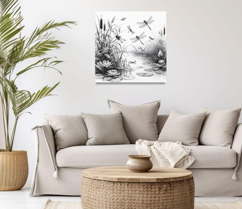 Canvas wall art above a couch. The canvas wall art features an elegant black and white line art scene of dragonflies gracefully hovering over a tranquil pond.