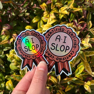 May include: Two circular award ribbon stickers with a scalloped edge and two tails. The centre features the text A.I. SLOP in black, surrounded by the repeated word CERTIFIED. The design uses a metallic, holographic finish with red accents.