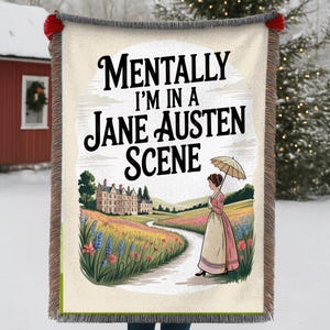 May include: A beige throw blanket with a decorative fringe and the text "Mentally I'm in a Jane Austen Scene." The blanket features a colourful illustration of a woman with an umbrella walking on a path near a mansion.