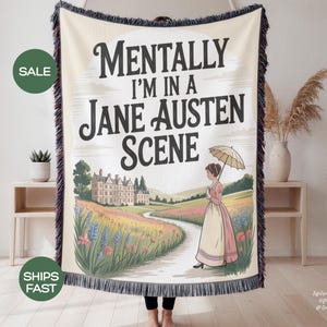 May include: Cream-coloured woven throw blanket with the text "Mentally I'm in a Jane Austen Scene." The design features a woman with an umbrella walking on a path towards a manor house. The blanket has a black fringe.