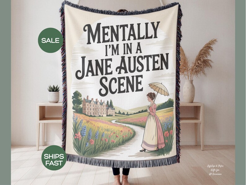 May include: Cream-coloured woven throw blanket with the text "Mentally I'm in a Jane Austen Scene." The design features a woman with an umbrella walking on a path towards a manor house. The blanket has a black fringe.