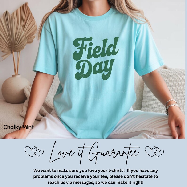 May include: A light blue t-shirt with the words "Field Day" in a retro green font. The shirt is a soft, comfortable material. The text "Chalky Mint" is in the lower left corner. The text "Love it Guarantee" is at the bottom.