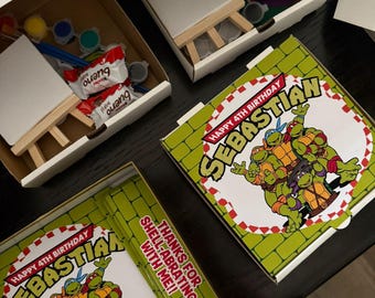 May include: Several open white cardboard boxes containing art supplies and treats. Each box includes a small canvas, a wooden easel, paint pots, and candy. The boxes are decorated with a Teenage Mutant Ninja Turtles theme, with the text "Happy 4th Birthday Sebastian".