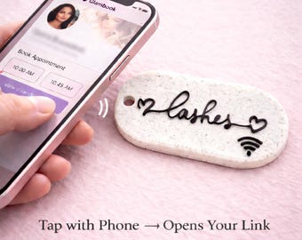 May include: A white, rectangular keychain with the word "lashes" in black script, two heart symbols, and a Wi-Fi symbol. The keychain is being tapped by a smartphone displaying a booking app. The text reads "Tap with Phone → Opens Your Link."