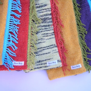 May include: Six colourful fabric strips with fringe trim and the text "Sami Bop" on each strip.