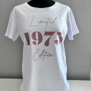 Könnte beinhalten: Weißes T-Shirt mit einer pinkfarbenen Grafik, auf der "Limited 1975 Edition" steht.