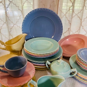 May include: A set of vintage pastel-colored ceramic teacups, saucers, and serving dishes. The set includes a teapot, creamer, sugar bowl, and a variety of plates in shades of blue, green, yellow, and pink.