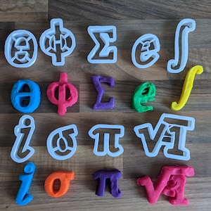 May include: An assortment of mathematical symbols and Greek letters, including integral, sigma, and pi, are displayed. Some are white plastic cookie cutters, while others are colorful play dough shapes in blue, pink, purple, green, and orange.