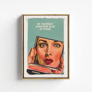 Peut inclure: Une impression d'art encadrée présentant une illustration de style vintage d'une personne tenant un miroir de poche. L'œuvre affiche le texte BE YOURSELF EVERYONE ELSE IS TAKEN en lettres blanches sur un fond sarcelle, avec un reflet de visage détaillé.