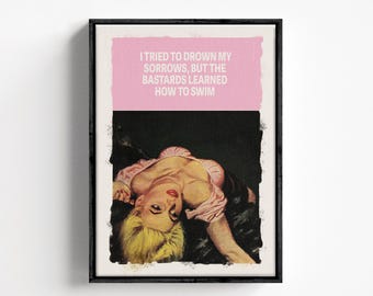 May include: A framed wall art print featuring a blonde person in a pink top lying down against a black background. The top section is a solid pink block with the white text: I TRIED TO DROWN MY SORROWS, BUT THE BASTARDS LEARNED HOW TO SWIM.