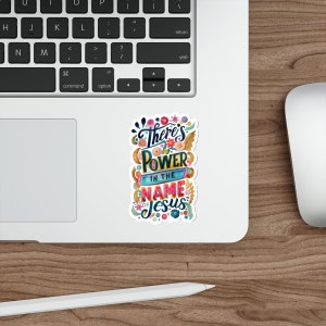 May include: A colorful sticker with the text "There's Power in the Name of Jesus" surrounded by flowers.