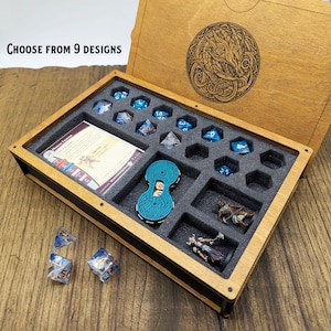 Può includere: Scatola di dadi in legno con un inserto in schiuma che contiene dadi blu, pedine e una carta. Il coperchio della scatola presenta un disegno inciso e il testo "Choose from 9 designs".
