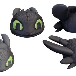 May include: Four black dragon head sculptures with green eyes. The dragon heads are in different poses, including a front view, side view, and top view. The sculptures have textured details and are set against a white background.