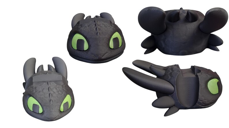 May include: Four black dragon head sculptures with green eyes. The dragon heads are in different poses, including a front view, side view, and top view. The sculptures have textured details and are set against a white background.