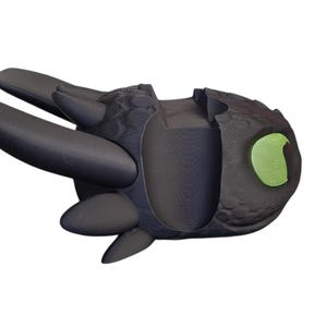 May include: A black dragon figurine with a textured body, large black wings, and a green eye. The dragon is in a flying pose, with its wings spread out. The figurine is likely a collectible or toy.
