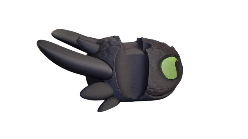 May include: A black dragon figurine with a textured body, large black wings, and a green eye. The dragon is in a flying pose, with its wings spread out. The figurine is likely a collectible or toy.
