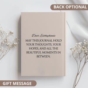 Op de afbeelding: Een beige notitieboek met de tekst "Dear Esthephanie, May this journal hold your thoughts, your hopes, and all the beautiful moments in between." De woorden "Back Optional" en "Gift Message" zijn ook zichtbaar.