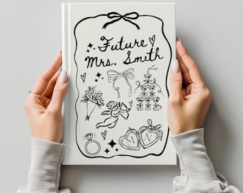 Op de afbeelding: Een wit notitieboek met een zwart handgetekend ontwerp. Het ontwerp bevat de tekst "Future Mrs. Smith", harten, een boeket, een strik, champagneglazen, een engel, een ring en twee harten met de letters "M" en "N".