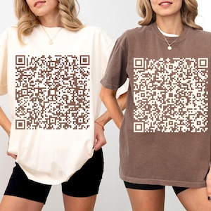 May include: Two women wearing oversized t-shirts with a brown and white QR code design. The t-shirts are available in cream and brown.
